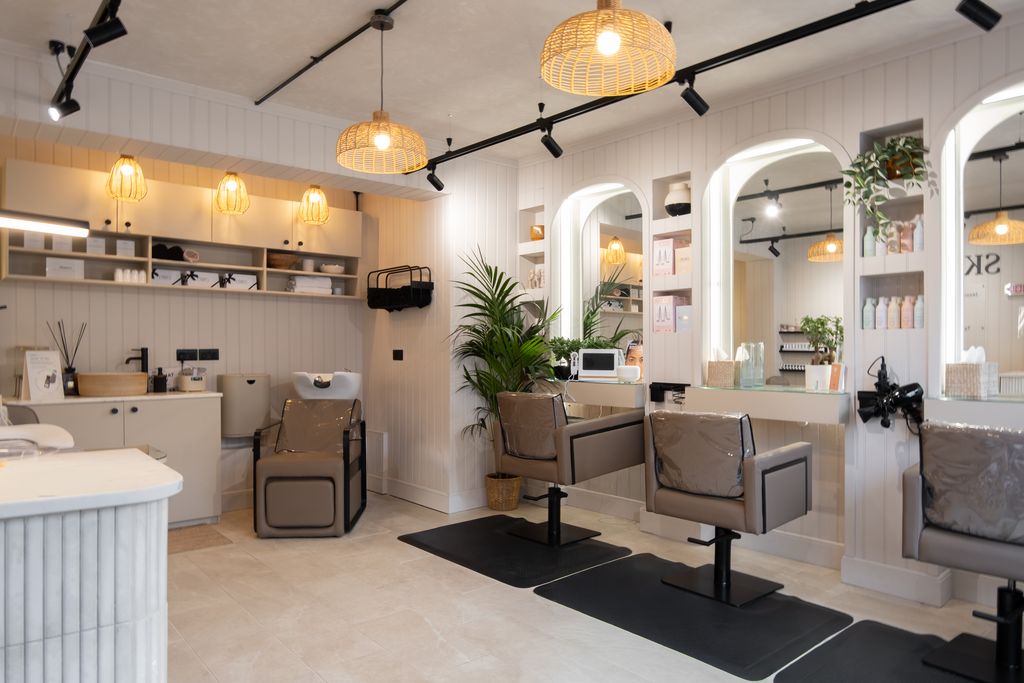 The hair and beauty floor at Skin & Co Morpeth, with arched mirrors, rattan pendant lights and styling chairs